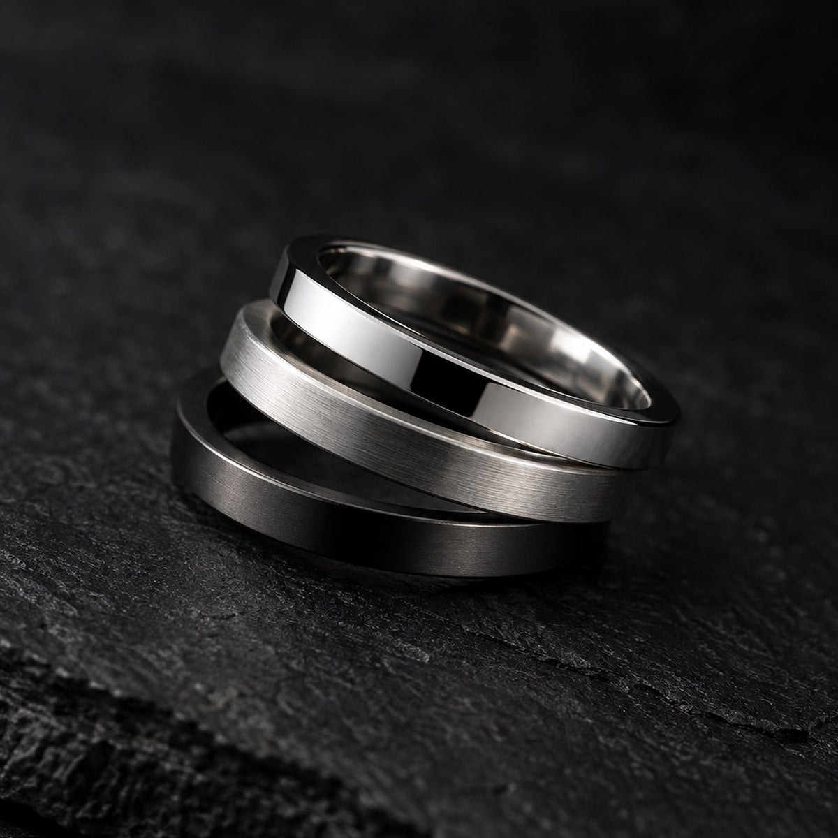 Set of three stainless steel stackable band rings in silver, brushed, and gunmetal